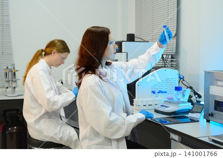 Two Female Scientists Working in Modern Research Laboratory with Equipment and Test Tubes 141001766