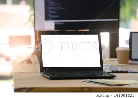 Laptop with Blank White Screen Mockup on Developer Desk with Monitor Showing Code Laptop with Blank White Screen Mockup on Developer Desk with Monitor Showing Code 141001823