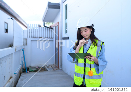 Young Asian Female Engineer Inspecting Construction Site with Digital Tablet and Safety Helmet Young Asian Female Engineer Inspecting Construction Site with Digital Tablet and Safety Helmet 141001852