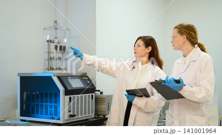 Two Female Scientists Operating Freeze Dryer Machine in Modern Laboratory with Clipboard and Tablet Two Female Scientists Operating Freeze Dryer Machine in Modern Laboratory with Clipboard and Tablet 141001964