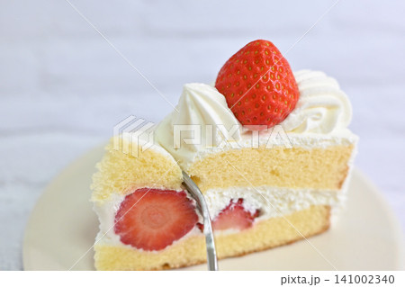 白いお皿にのったいちごのショートケーキにフォークを入れた写真 141002340