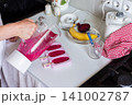 Person uses a blender to mix strawberries, bananas, beets, and Greek yogurt in a kitchen. Ice cream mixture fills molds while kitchen items and fruit are nearby on the counter 141002787