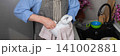A man stands in the kitchen wiping clean dishes with a cloth. He wears an apron and focuses on his task. The kitchen has a sink and some dishes on the counter, banner 141002881
