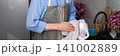 A man stands in the kitchen wiping clean dishes with a cloth. He wears an apron and focuses on his task. The kitchen has a sink and some dishes on the counter, banner 141002889