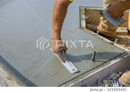Masonry worker is applying finishing touches to newly poured concrete slab surface at construction site Masonry worker is applying finishing touches to newly poured concrete slab surface at construction site 141003491