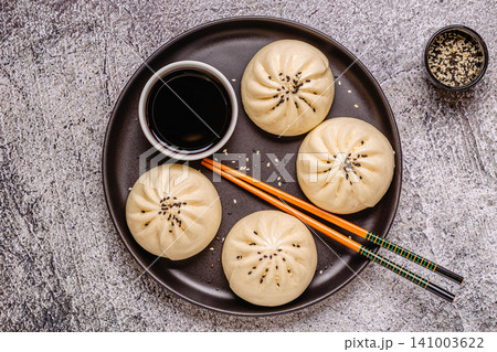 Steamed buns with savory filling served on a black plate 141003622