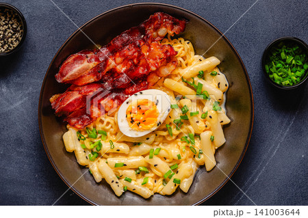 Korean street food - creamy rapokki served with bacon and egg. Korean street food - creamy rapokki served with bacon and egg. 141003644