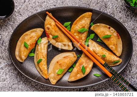 Dumplings served on a black plate with green onions Dumplings served on a black plate with green onions 141003721