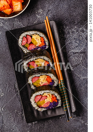 A black plate filled with kimbap (or gimbap) that have colorful fillings. 141003730