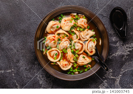 Dumplings served in a bowl with broth and green onions. Dumplings served in a bowl with broth and green onions. 141003745