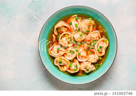 Dumplings served in a bowl with broth and green onions. Dumplings served in a bowl with broth and green onions. 141003746