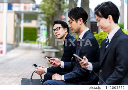 バス停のベンチに座ってバスを待つスーツ姿の男性 バス停のベンチに座ってバスを待つスーツ姿の男性 141003831