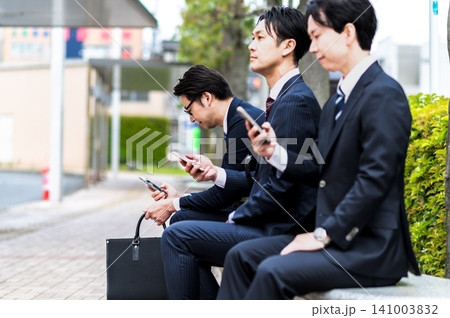 バス停のベンチに座ってバスを待つスーツ姿の男性 バス停のベンチに座ってバスを待つスーツ姿の男性 141003832