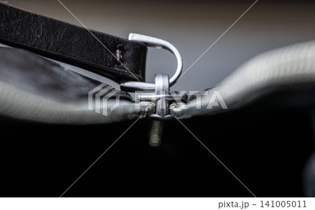 Close-up of a silver zipper slider with leather pull tab on a dark bag, shallow depth of field Close-up of a silver zipper slider with leather pull tab on a dark bag, shallow depth of field 141005011