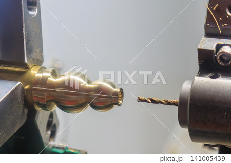 High-precision CNC lathe machine performing a hole making drilling process on brass material parts. High-precision CNC lathe machine performing a hole making drilling process on brass material parts. 141005439