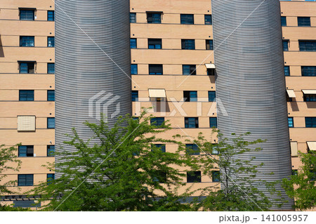 Modern urban architecture with metallic towers and leafy green trees Modern urban architecture with metallic towers and leafy green trees 141005957