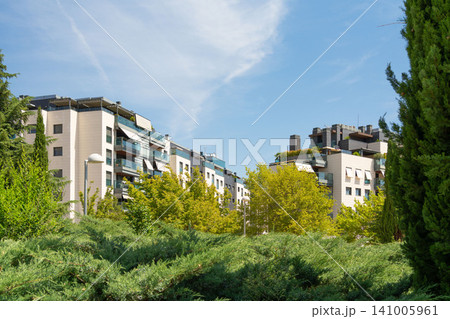 Residential buildings surrounded by trees and bushes under clear sky 141005961