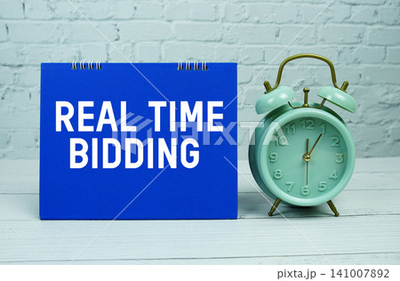 Real Time Bidding text with Mint Green Alarm Clock on wooden Background Real Time Bidding text with Mint Green Alarm Clock on wooden Background 141007892