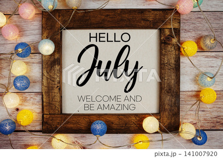 Hello July text with LED cotton ball decoration on wooden background 141007920