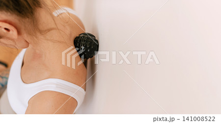 Woman Using Massage Ball Against Wall 141008522