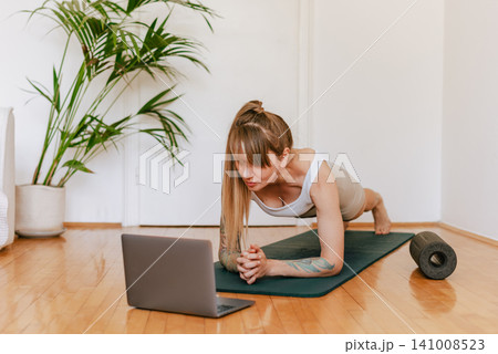 Woman Standing in Plank Watching Online Workout Class Woman Standing in Plank Watching Online Workout Class 141008523