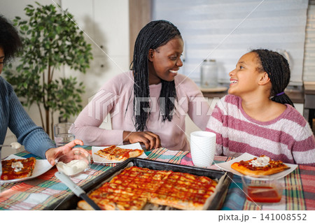 Happy family enjoying homemade pizza dinner at home Happy family enjoying homemade pizza dinner at home 141008552
