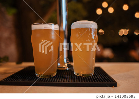 Craft beer pints sitting on bar counter at night Craft beer pints sitting on bar counter at night 141008695