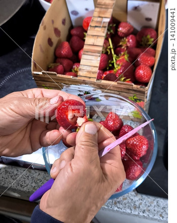 Cutting off strawberry hulls with a knife in the kitchen 141009441