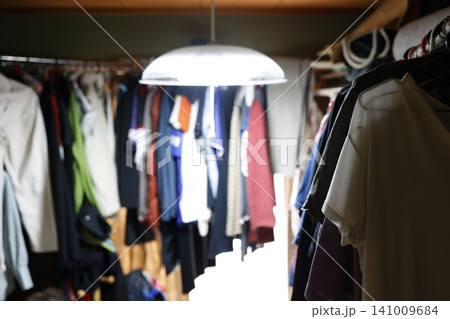 片付けられていない乱雑な部屋。大量の服で溢れかえったクローゼット。洋服整理 片付けられていない乱雑な部屋。大量の服で溢れかえったクローゼット。洋服整理 141009684