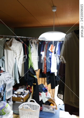 片付けられていない乱雑な部屋。大量の服で溢れかえったクローゼット。洋服整理 片付けられていない乱雑な部屋。大量の服で溢れかえったクローゼット。洋服整理 141009685