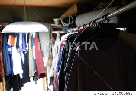 片付けられていない乱雑な部屋。大量の服で溢れかえったクローゼット。洋服整理 141009686