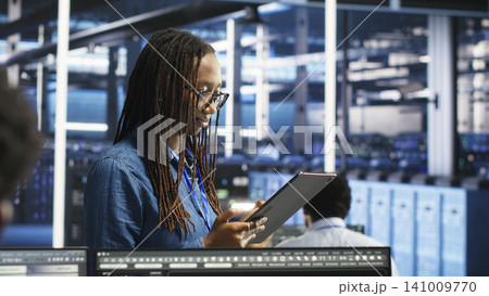 Woman in data center working with AI visualization insights on tablet device to improve system health. 141009770
