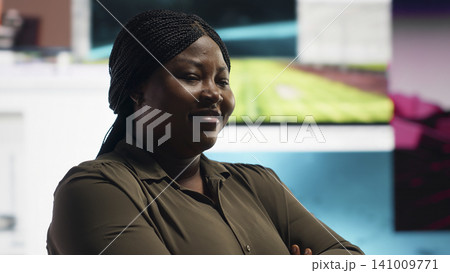 Satisfied user enjoying endless entertainment in digital media setting. Happy African American woman in front of giant digital wall streaming online videos content. Satisfied user enjoying endless entertainment in digital media setting. Happy African American woman in front of giant digital wall streaming online videos content. 141009771