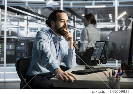System administrator working with computer in server facility, managing server virtualization, running scripts. System administrator working with computer in server facility, managing server virtualization, running scripts. 141009925
