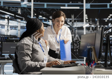 Smiling data center team works with digital devices while reviewing systems, scripts and server infrastructure. 141010135