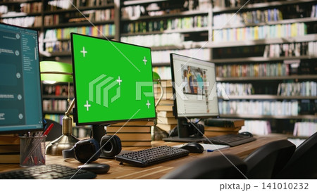 Green screen desktop with multiple monitors showing interfaces in library, IT class computer lab with mockup. Library workspace frame beside blurred screens, books, keyboard and headphones. 141010232