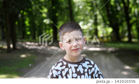 Child smiling, in park, with pathway, trees, with clothing texture, from a frontal perspective, with brown, white accents, and happy mood, clear detail, natural detail. Child smiling, in park, with pathway, trees, with clothing texture, from a frontal perspective, with brown, white accents, and happy mood, clear detail, natural detail. 141010356