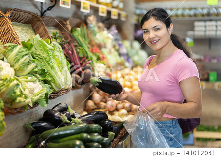 Adult woman choosing eggplants at vegetable shop Adult woman choosing eggplants at vegetable shop 141012031