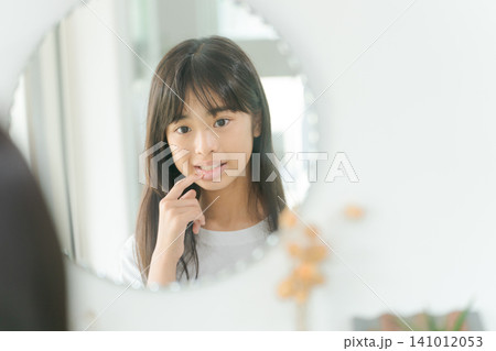 鏡で口元を見る小学生女子 141012053