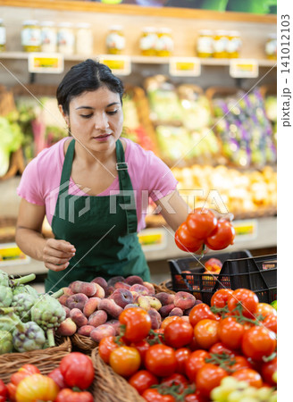 Woman worker seller in grocery vegetable shop and tomato 141012103