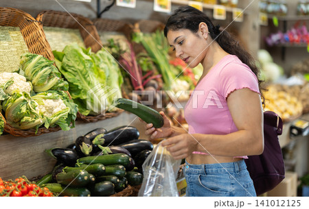 Girl shopper choosing ripe fresh zucchini at street market Girl shopper choosing ripe fresh zucchini at street market 141012125