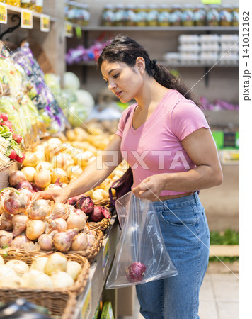 Female shopper selects onions grocery supermarket Female shopper selects onions grocery supermarket 141012162