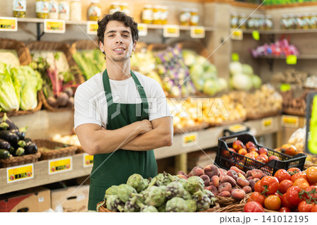 Portrait of successful male salesperson wearing an apron in grocery store interior Portrait of successful male salesperson wearing an apron in grocery store interior 141012195