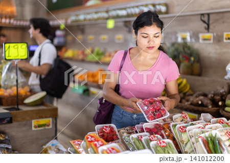 Female customer choosing vegetables and fruits in packaging at grocery store Female customer choosing vegetables and fruits in packaging at grocery store 141012200