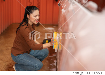 woman washing car with sponge and foam in a self-service car wash station woman washing car with sponge and foam in a self-service car wash station 141012221