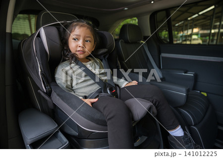 preschool child girl sitting in car seat and looking out of the window, safety baby chair travelling preschool child girl sitting in car seat and looking out of the window, safety baby chair travelling 141012225
