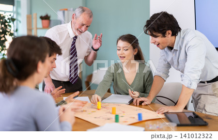 Young students and a teacher playing educational board game Young students and a teacher playing educational board game 141012322