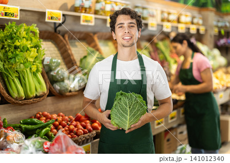 Man worker seller in grocery vegetable shop assort fruit cabbage Man worker seller in grocery vegetable shop assort fruit cabbage 141012340