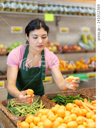 Woman worker seller in grocery vegetable shop assort fruit apricot Woman worker seller in grocery vegetable shop assort fruit apricot 141012369
