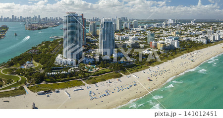 Aerial view of South Beach sandy surface with tourists relaxing on hot Florida sun. Miami Beach city with high luxury hotels and condos. Tourism infrastructure in southern USA Aerial view of South Beach sandy surface with tourists relaxing on hot Florida sun. Miami Beach city with high luxury hotels and condos. Tourism infrastructure in southern USA 141012451